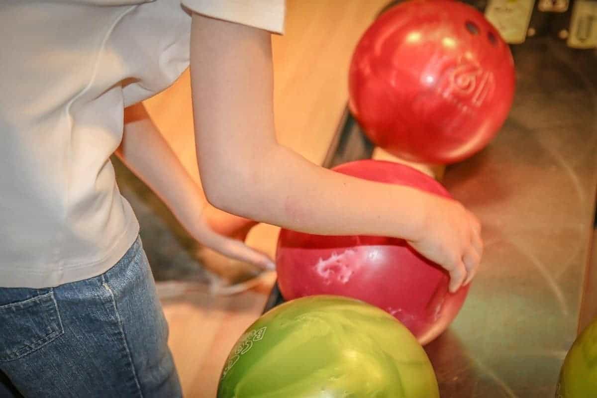 Person picking a bowling ball off of ball return rack