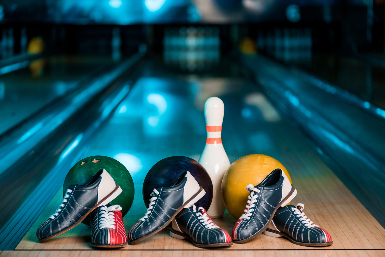 3 bowling balls setting at foul line with 3 pairs of shoes